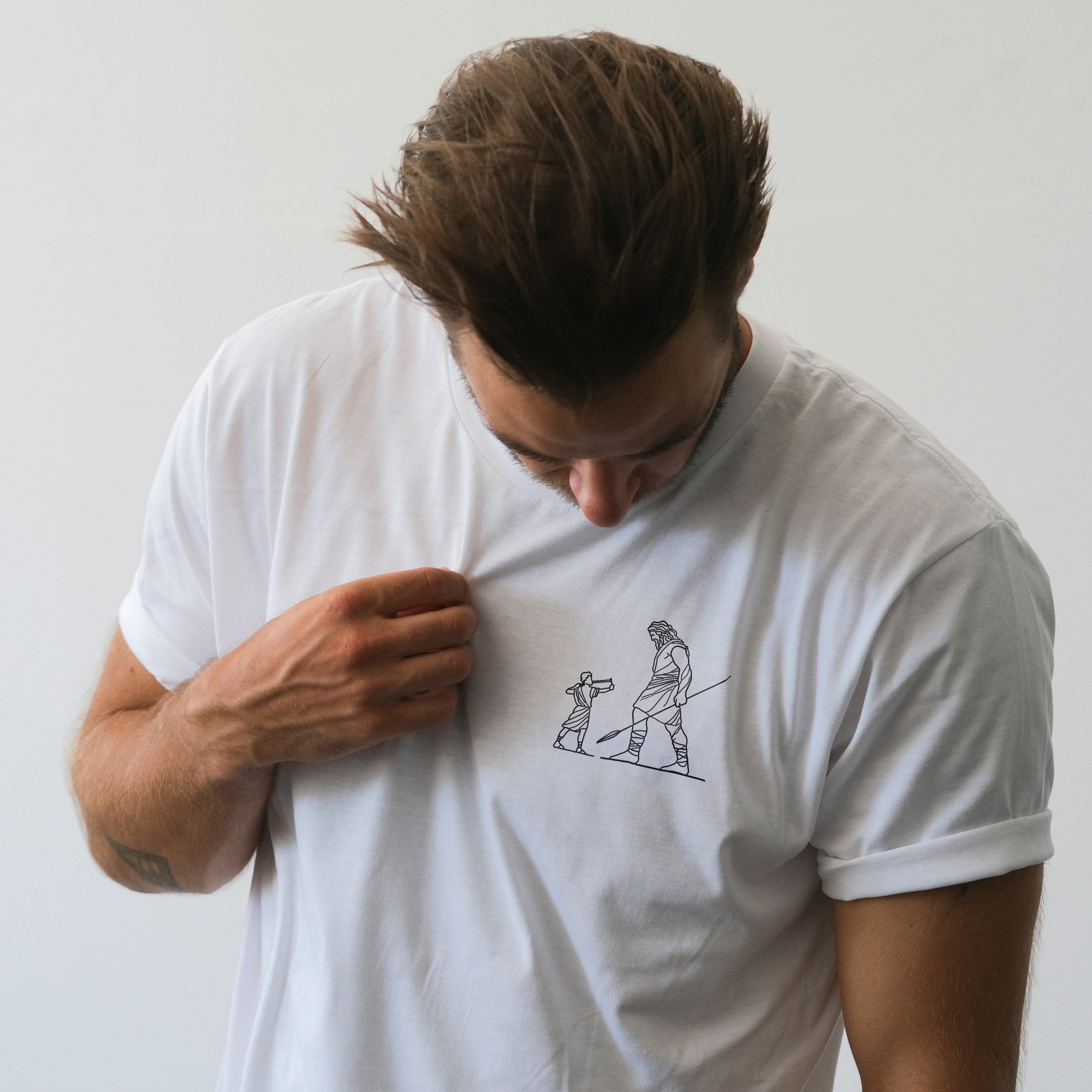 Man wearing a white t-shirt with a graphic design on a plain background