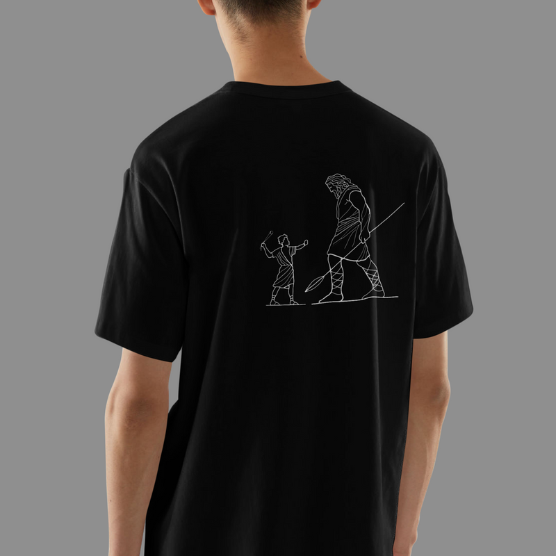 Person wearing a black t-shirt with a graphic design on the back against a gray background, front view
